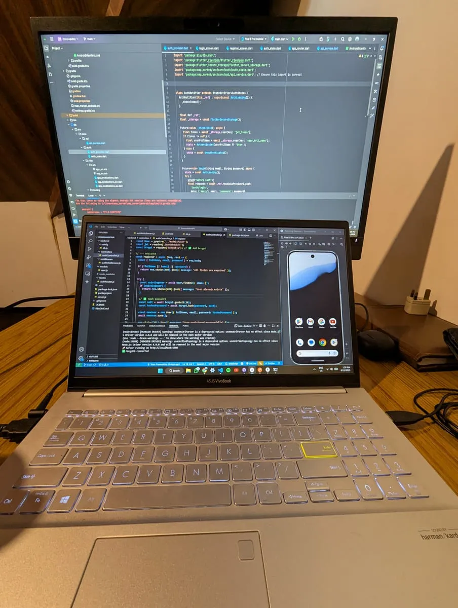 A laptop and external monitor showing Flutter code beside an Android device emulator.