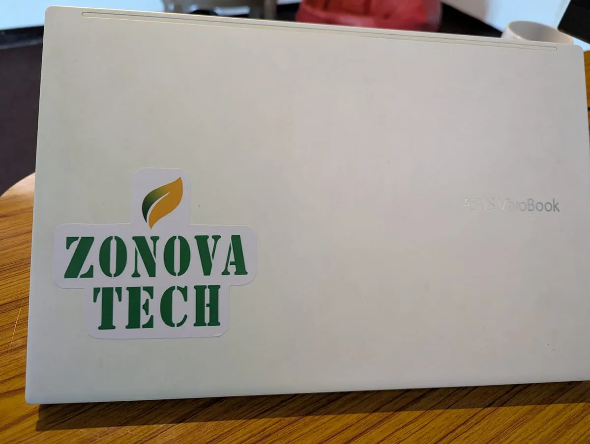 A laptop lid on a wooden desk with a Zonova Tech sticker on it.