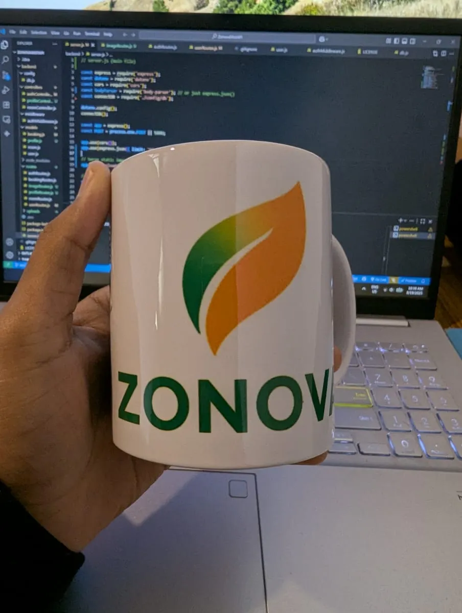 A hand holding a Zonova-branded mug in front of a screen full of Node.js server code.