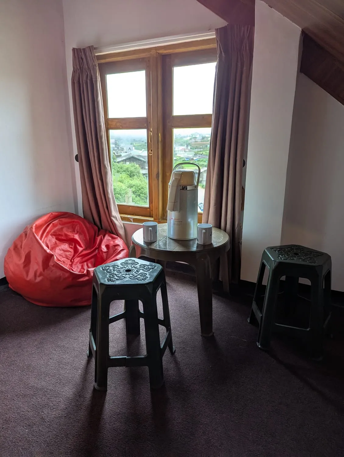 A corner of the Zonova Tech studio: a red beanbag, a tea flask and two mugs on a low table, beside a window looking out over Nuwara Eliya.